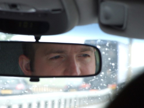 Looking back at that tailgater! Close up of man's eyes in rear view mirror